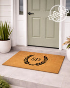 Doormat with initials 'S&D' on a light gray floor in front of a green door. [VARIANT: TWO INITIALS / NO BORDER]