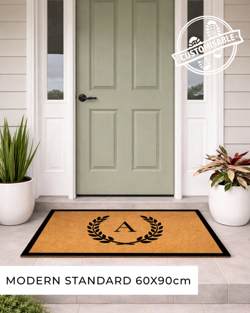 Doormat with a monogram in front of a green door on a porch. [VARIANT: SINGLE INITIAL / BORDER]