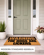 Doormat with 'Warning: The Dogs Are Lickers' text in front of a green door. [VARIANT: DOGS / LICKERS]