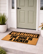 Doormat with 'Warning: The Dog is a Licker' text in front of a door. [VARIANT: DOG / LICKER]