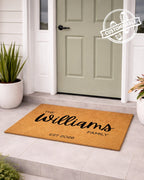 Personalized doormat with 'The Williams Family' text in front of a door. [VARIANT: STANDARD-EST]