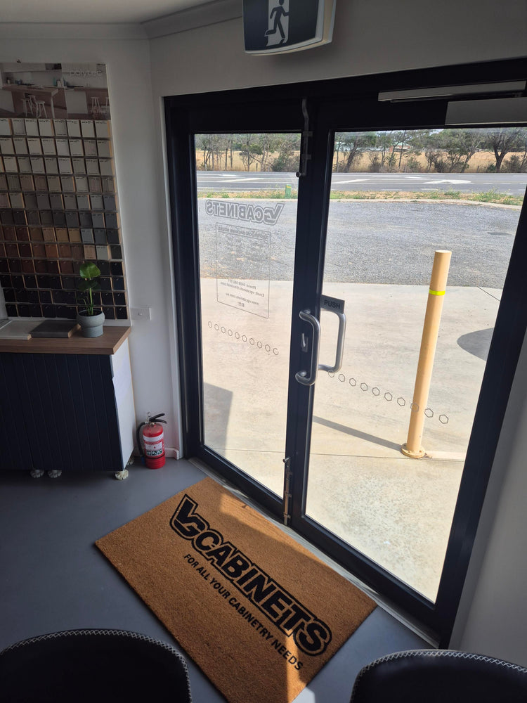 Doormat with 'VG Cabinets' logo in front of a glass door