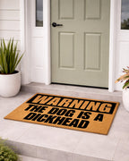 Doormat with humorous text on a front door step [variant: dog-dickhead]