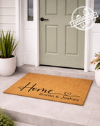Personalized doormat with 'Home Emma & Joshua' text in front of a green door.