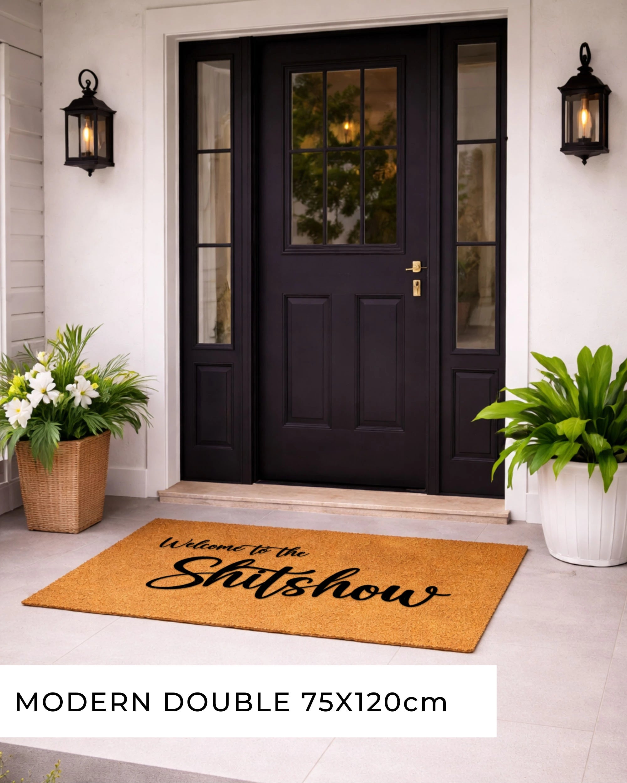 Doormat with 'NO CUNTS' text in front of a black door with glass panels, flanked by potted plants.